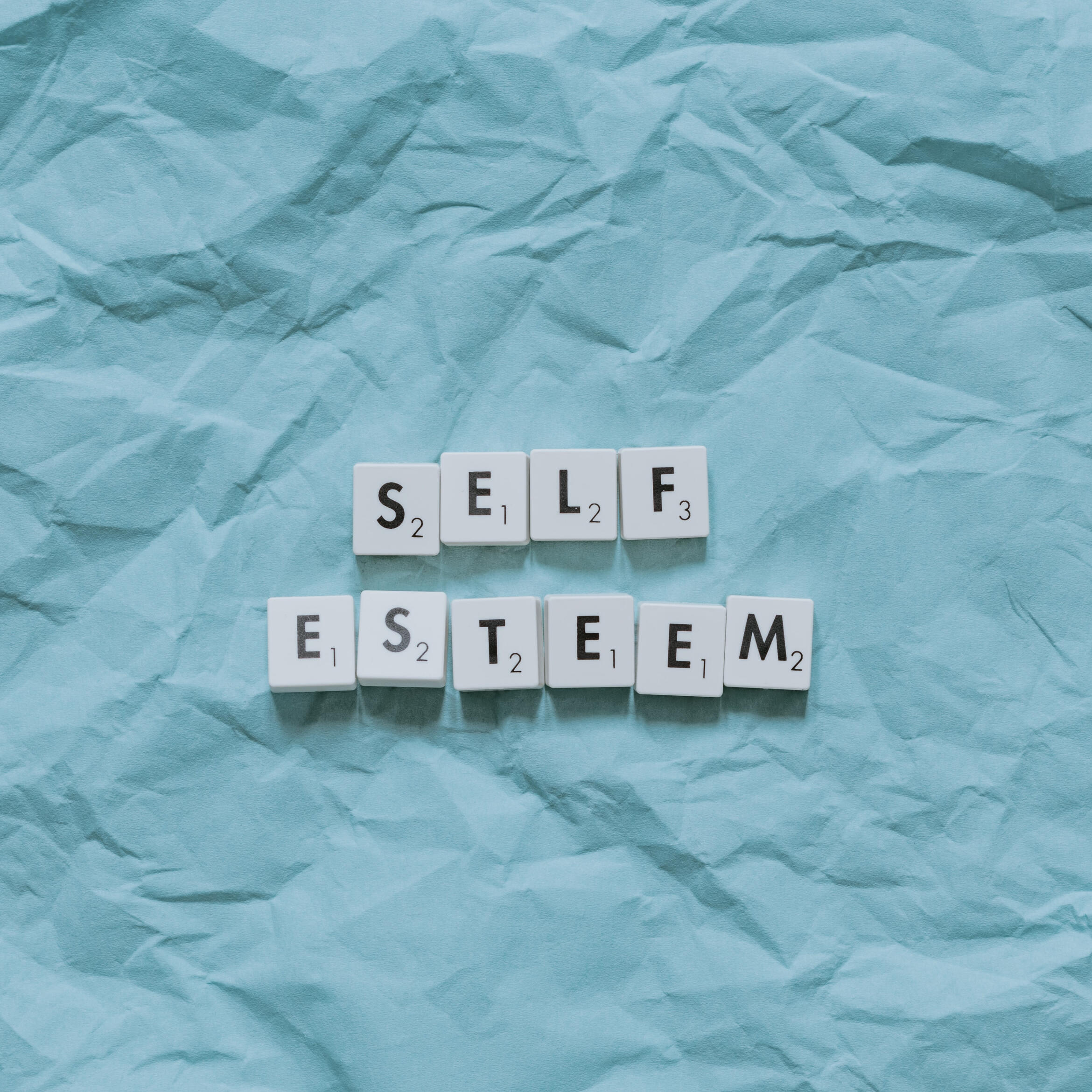 An image with white scrabble tiles spelling out "self esteem".