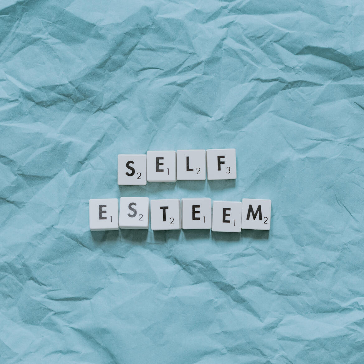 An image with white scrabble tiles spelling out "self esteem".